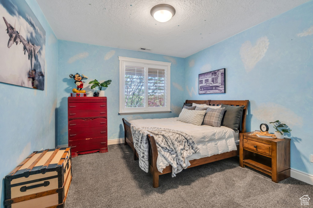 Carpeted bedroom featuring a textured ceiling and baseboards