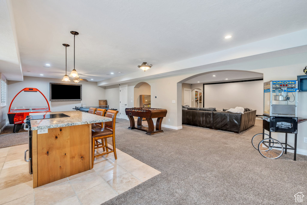 Kitchen featuring open floor plan, light carpet, arched walkways, recessed lighting, and a breakfast bar