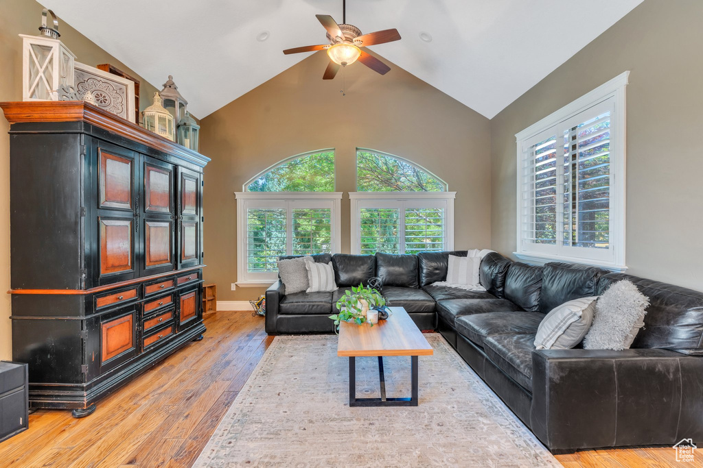 Living area with ceiling fan, plenty of natural light, hardwood / wood-style flooring, and high vaulted ceiling