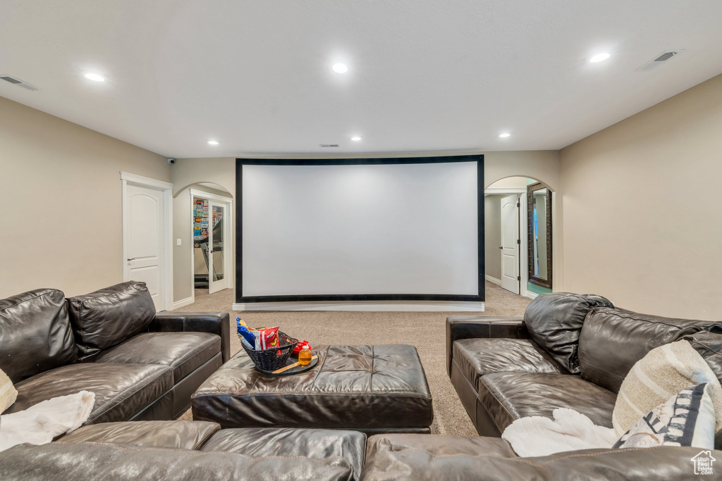 Home theater with arched walkways, light carpet, and recessed lighting