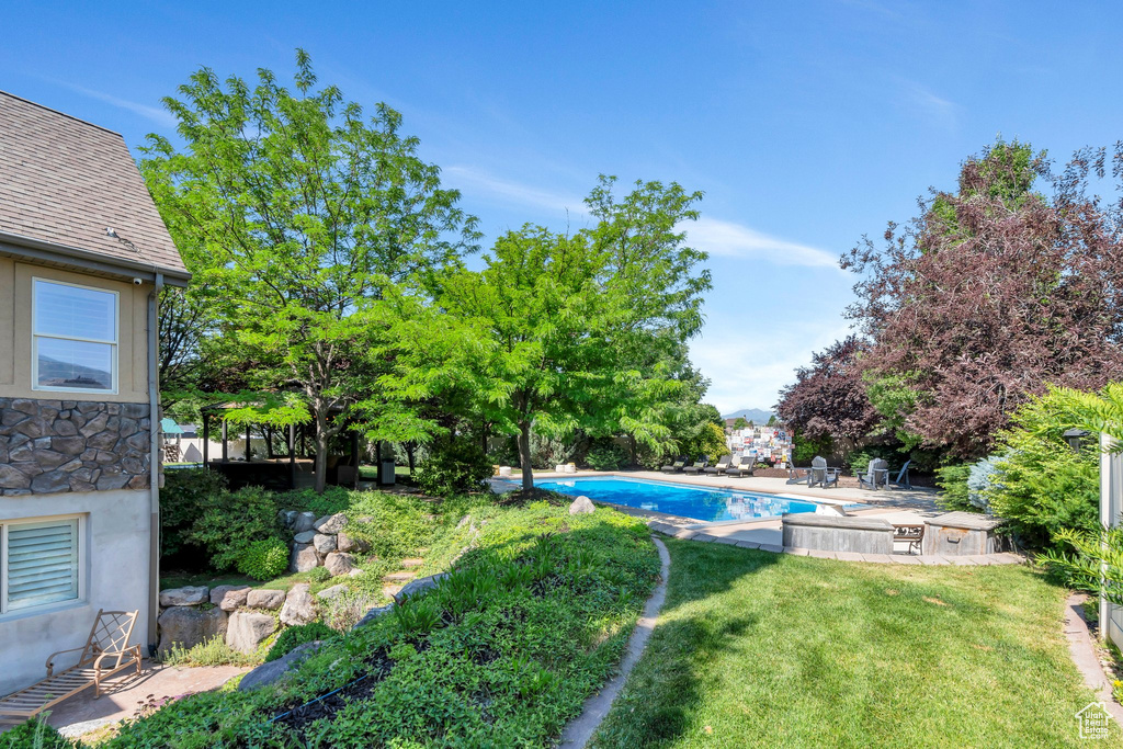 View of grassy yard with an outdoor pool and a patio area