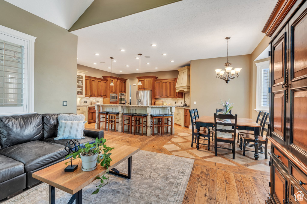 Living room with light wood-style flooring, a chandelier, and recessed lighting