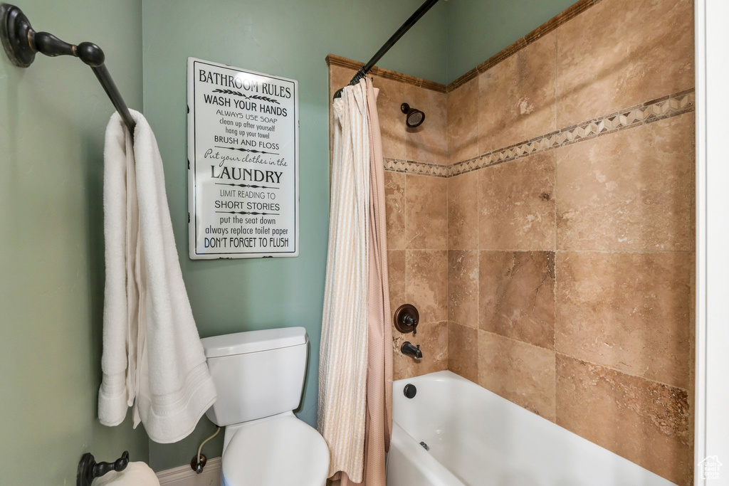 Bathroom featuring toilet and shower / bath combo with shower curtain