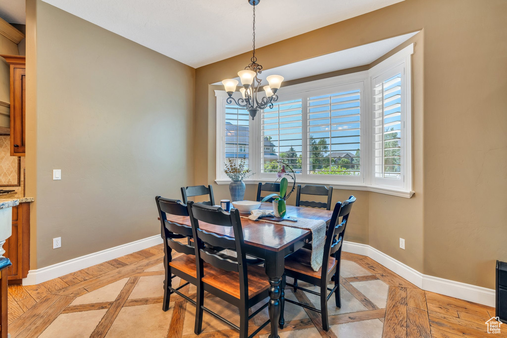 Dining space featuring inlaid floor details and a chandelier