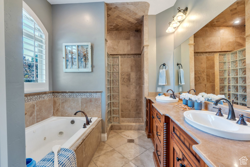 Bathroom featuring double vanity, a jetted tub, a stall shower, and tile patterned flooring