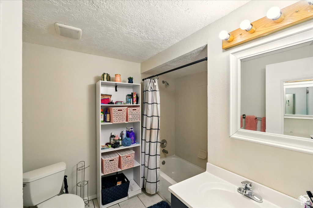 Full bath featuring shower / tub combo, vanity, tile patterned flooring, and a textured ceiling