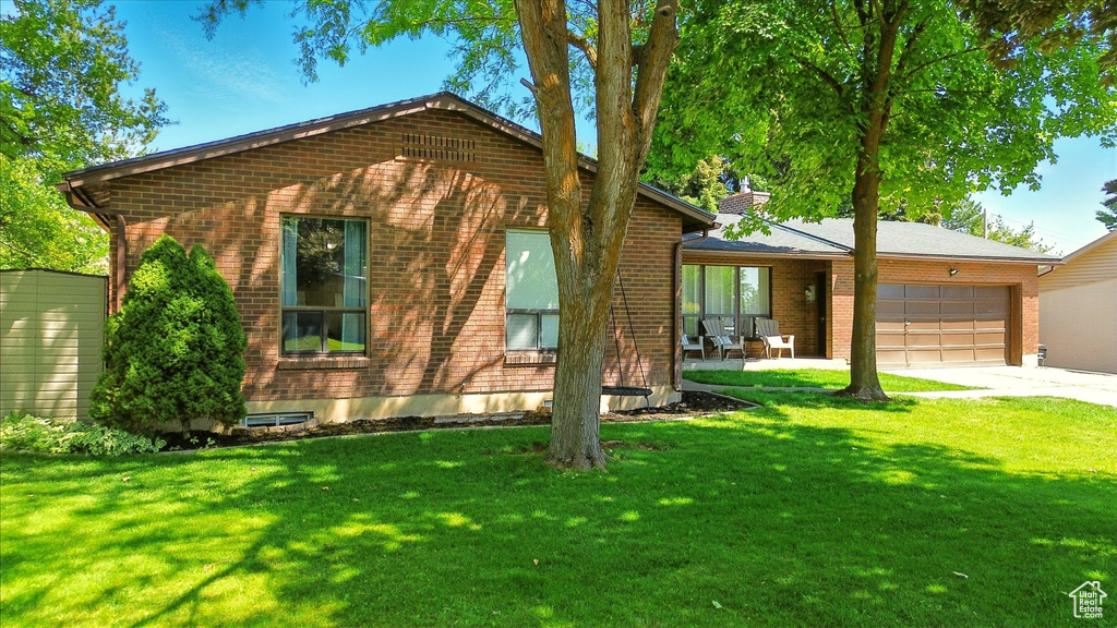 View of front of home featuring an attached garage, brick siding, a front lawn, and concrete driveway