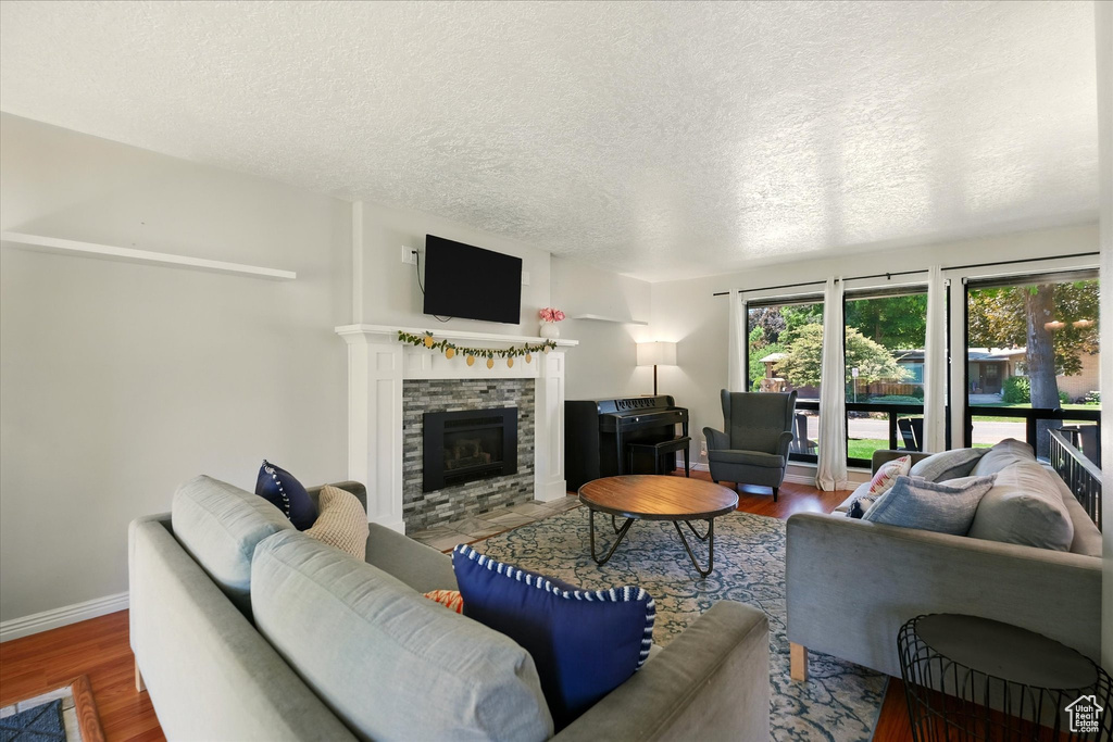 Living room featuring wood finished floors, a tile fireplace, and a textured ceiling