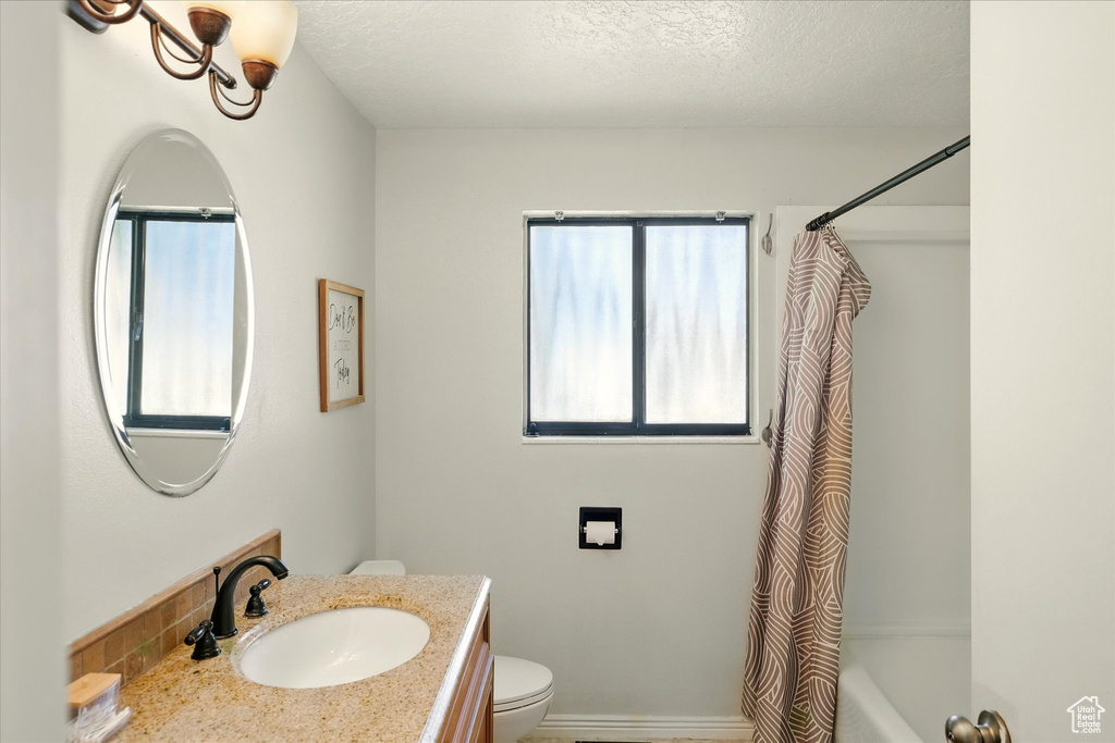 Bathroom featuring vanity, shower / bathtub combination with curtain, and a textured ceiling