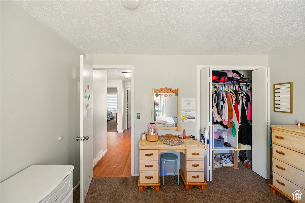 Bedroom featuring dark colored carpet, a textured ceiling, and a closet