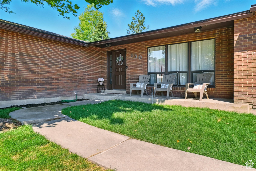Property entrance with brick siding and a yard