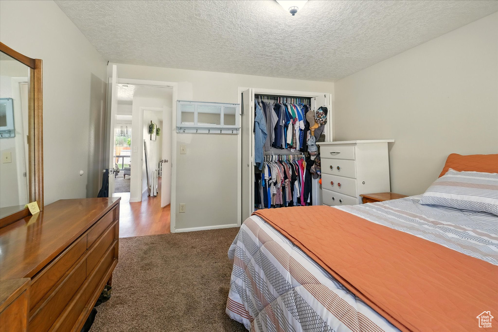 Carpeted bedroom with a closet and a textured ceiling