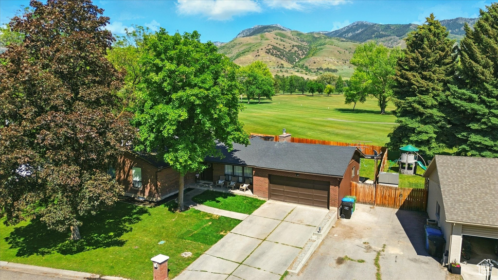 View of front of home with a mountain view, an attached garage, concrete driveway, and brick siding