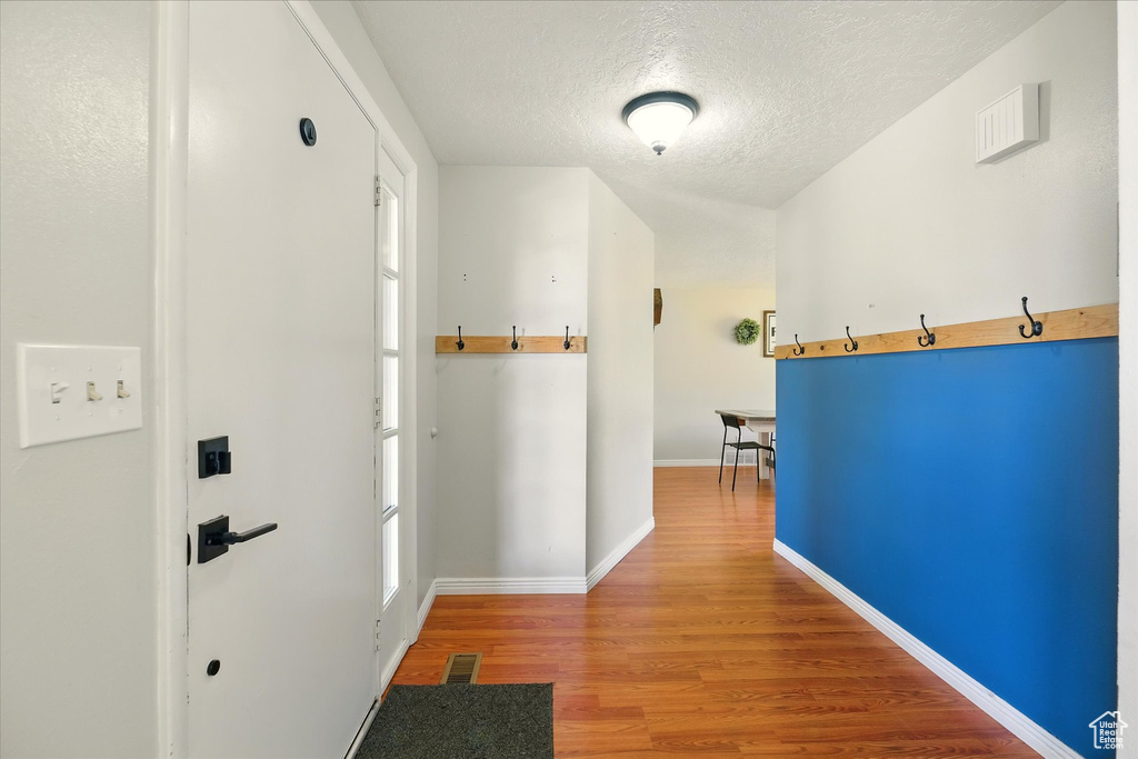 Hall featuring a textured ceiling and wood finished floors