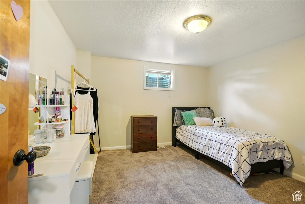 Carpeted bedroom with a textured ceiling and baseboards