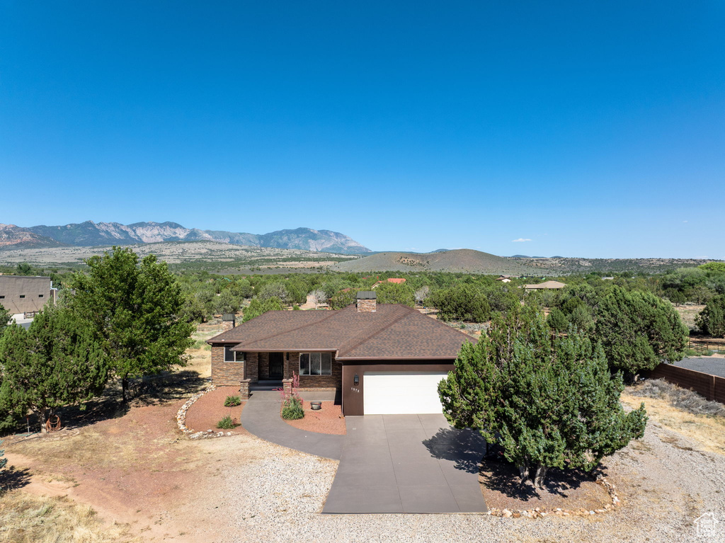 Ranch-style home with a garage, driveway, a chimney, a mountain view, and covered porch