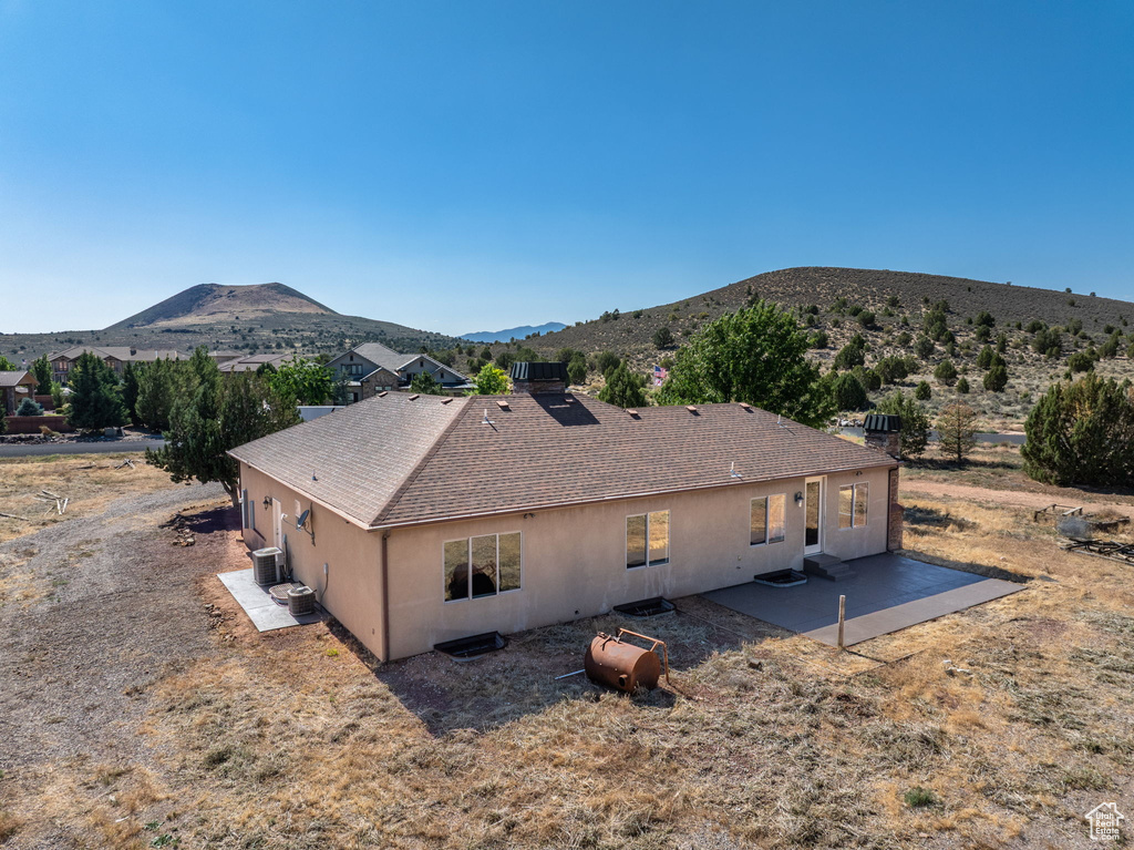Back of property featuring a patio area, a mountain view, roof with shingles, and stucco siding