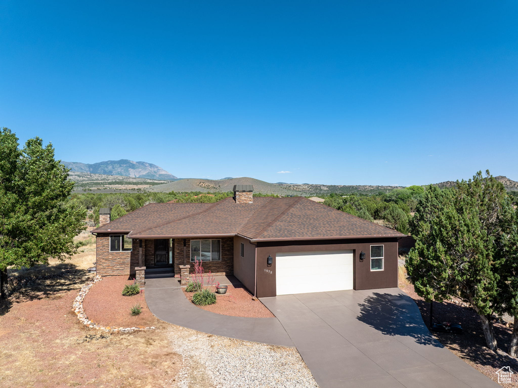 Ranch-style home with a chimney, a garage, concrete driveway, covered porch, and a mountain view