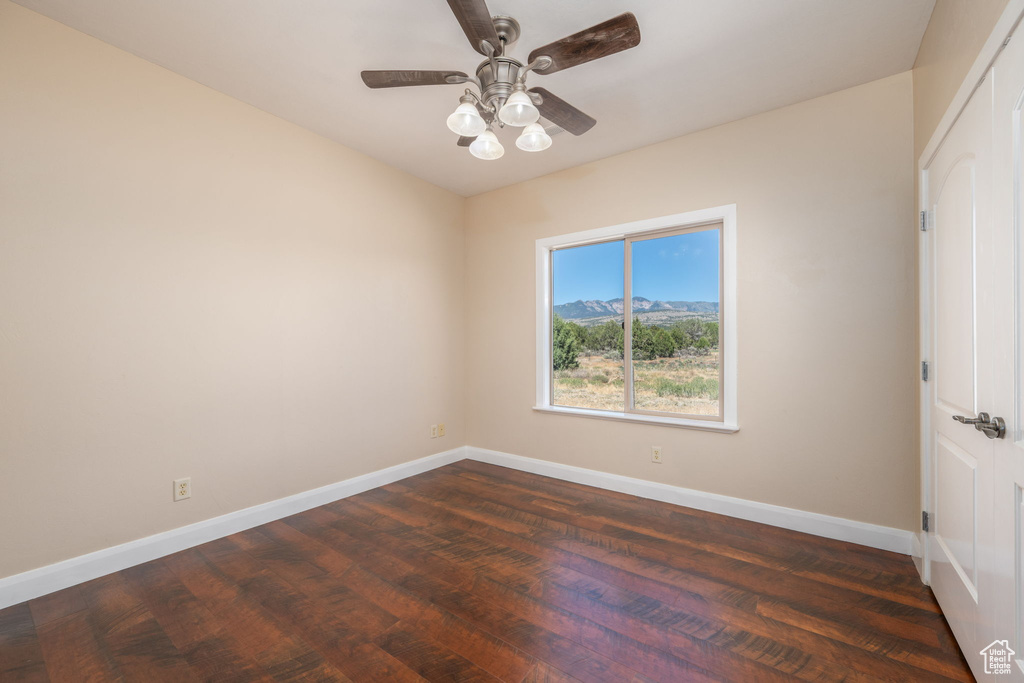 Spare room featuring dark wood-type flooring and a ceiling fan