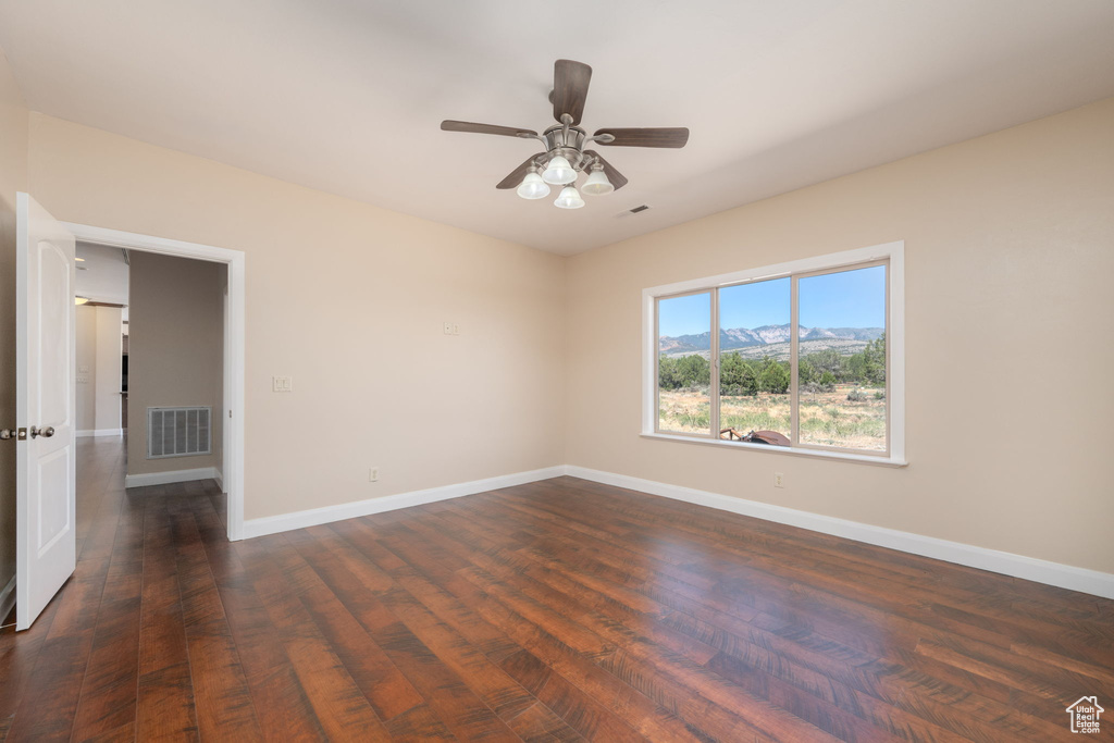 Empty room featuring dark wood-style flooring, ceiling fan, and a mountain view