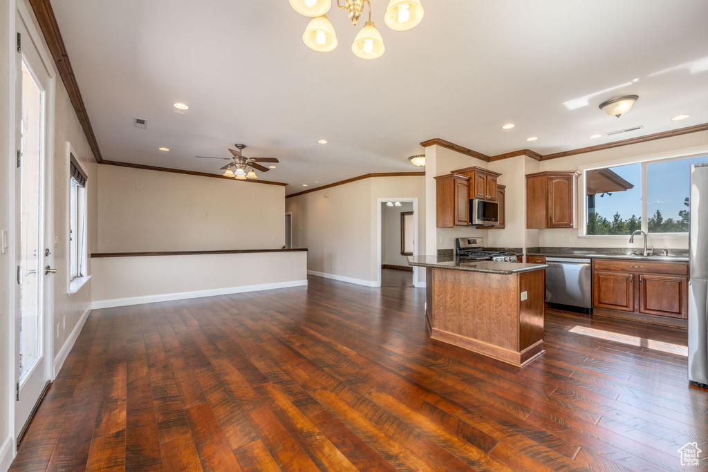 Kitchen featuring appliances with stainless steel finishes, ornamental molding, brown cabinets, dark wood-style flooring, and recessed lighting