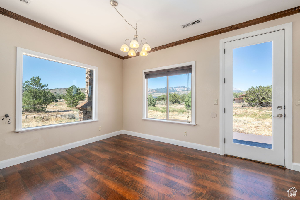 Unfurnished dining area featuring a chandelier, crown molding, dark wood-style floors, and a mountain view