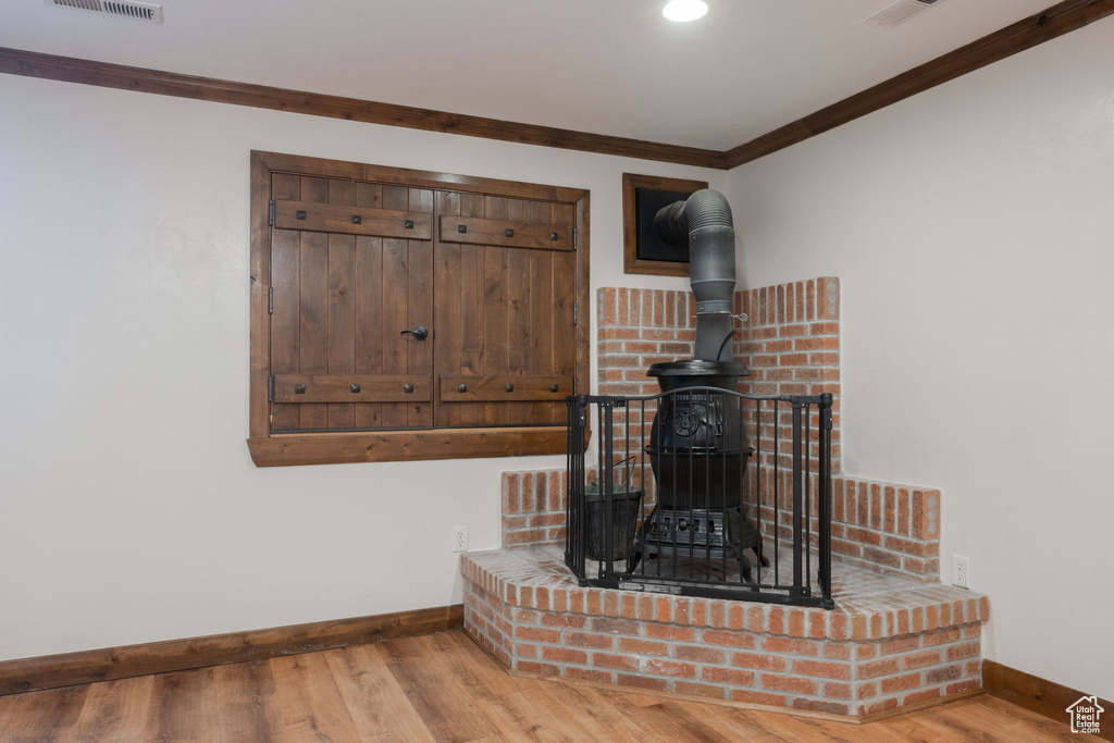 Detailed view of a wood stove, crown molding, and wood finished floors