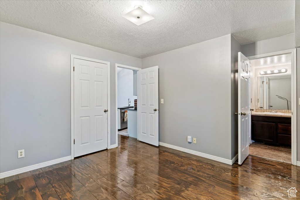 Unfurnished bedroom with wood finished floors, a textured ceiling, and connected bathroom