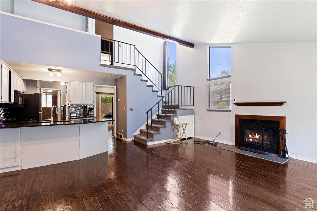 Unfurnished living room featuring dark wood finished floors, a fireplace with flush hearth, and stairs
