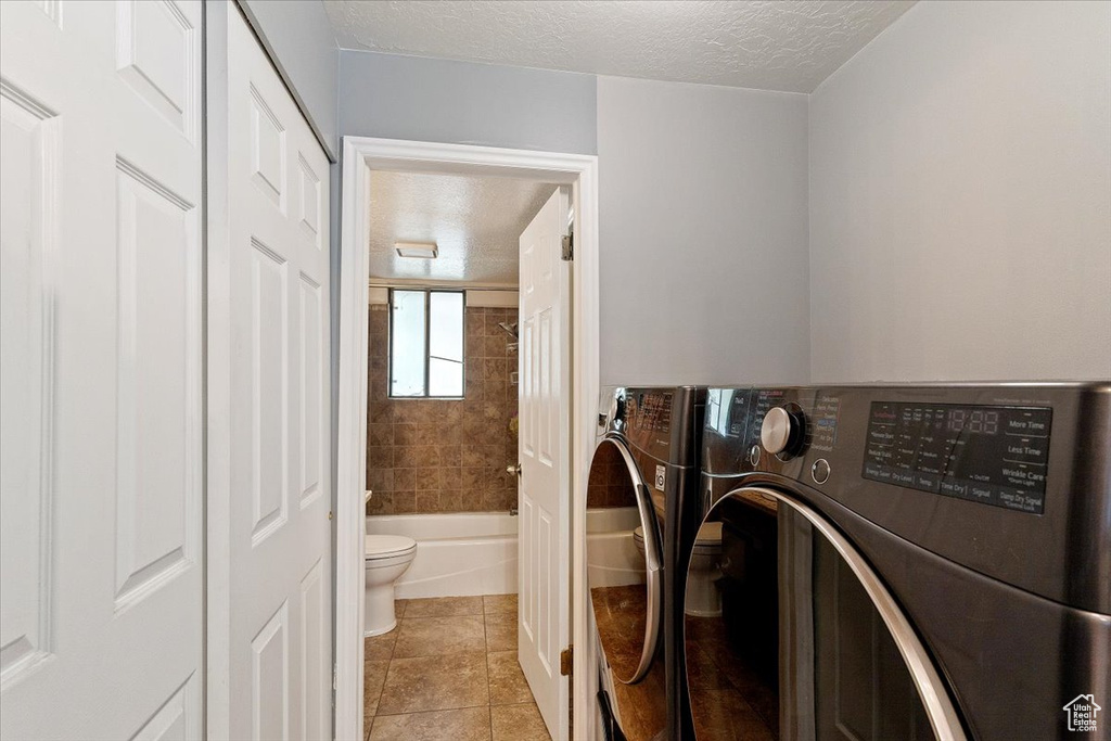 Laundry room featuring separate washer and dryer, a textured ceiling, and light tile patterned floors