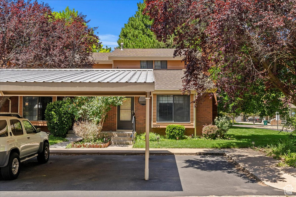 Multi unit property with covered parking, brick siding, entry steps, and roof with shingles