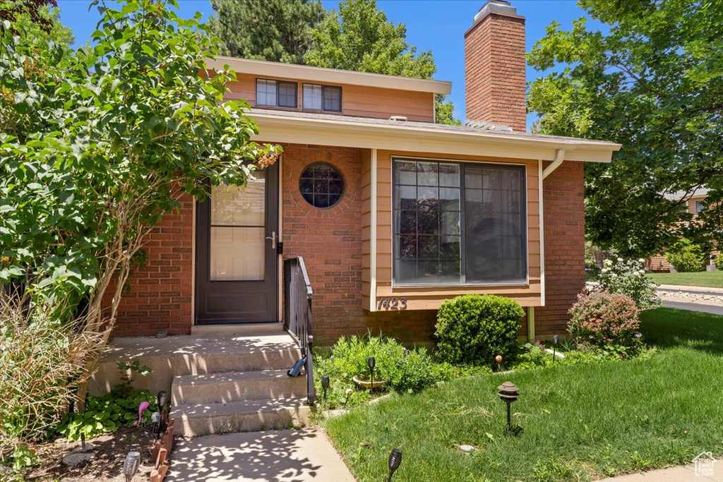 View of front of home with brick siding and a chimney