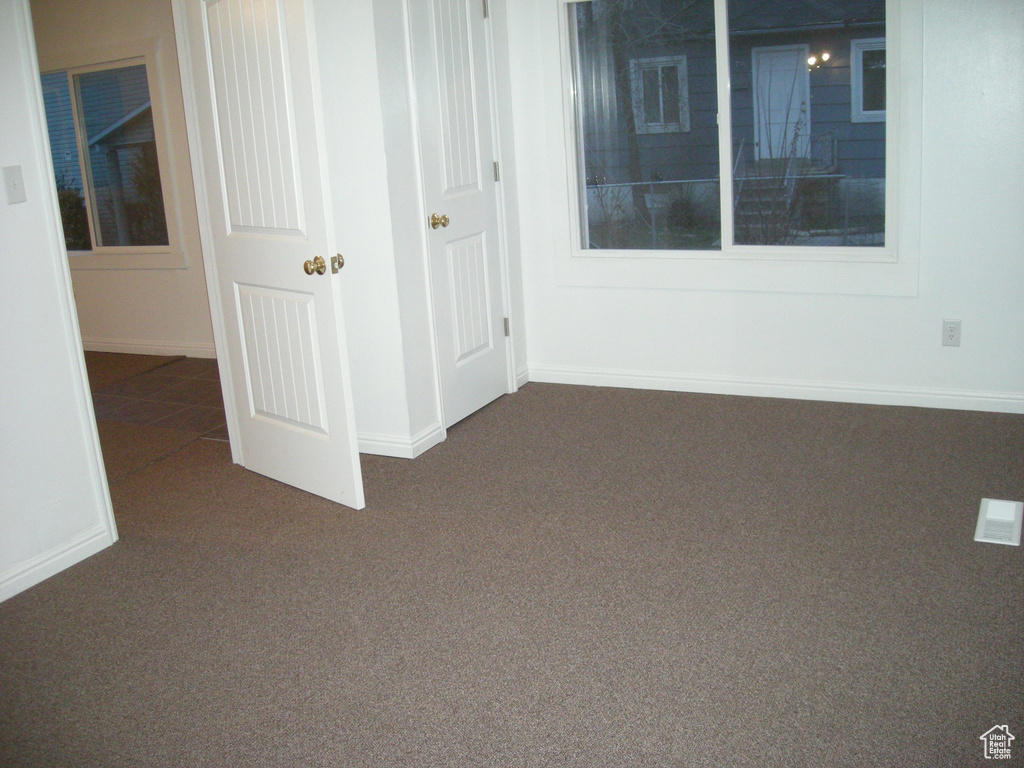 Empty room featuring dark colored carpet and baseboards