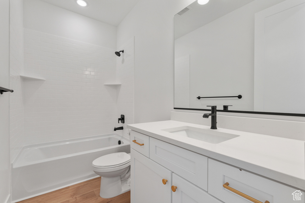 Bathroom with wood finished floors, vanity, shower / bath combination, and recessed lighting