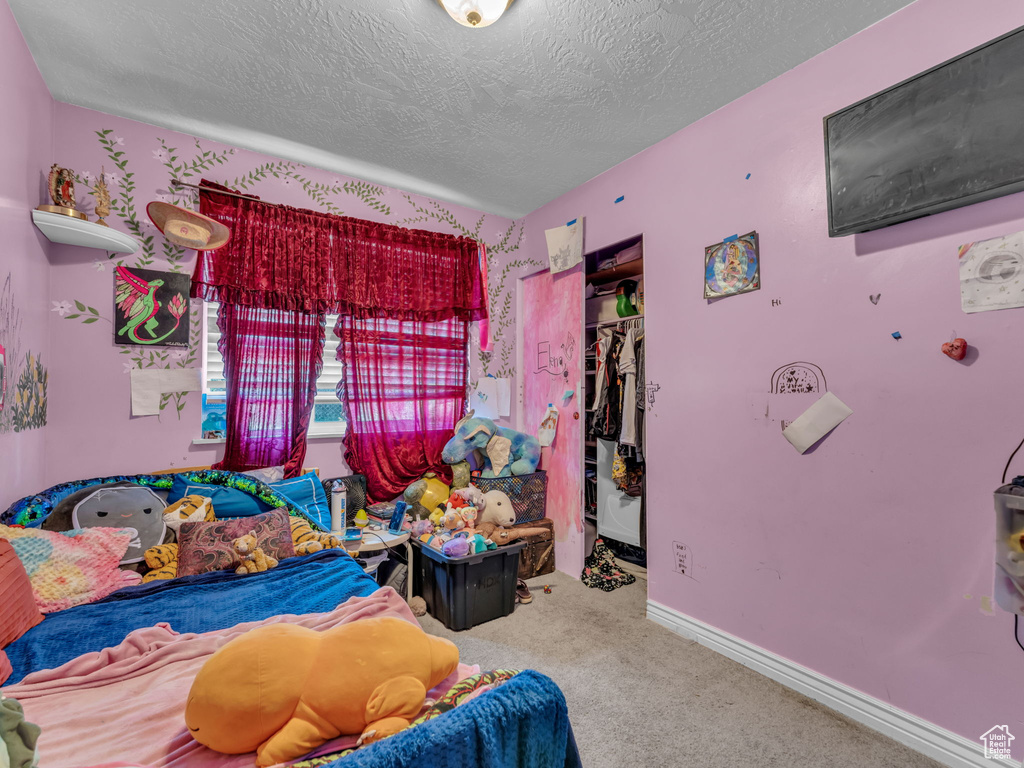 Carpeted bedroom featuring a closet, a textured ceiling, and a walk in closet