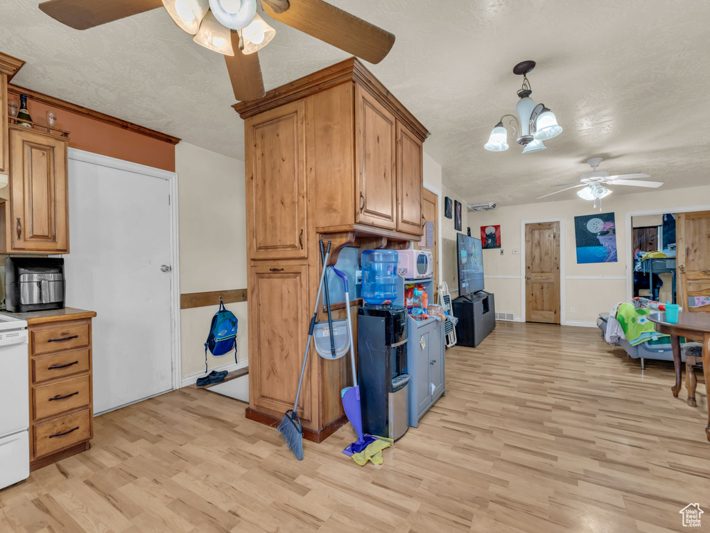 Kitchen with ceiling fan, light wood-style flooring, a textured ceiling, and brown cabinetry