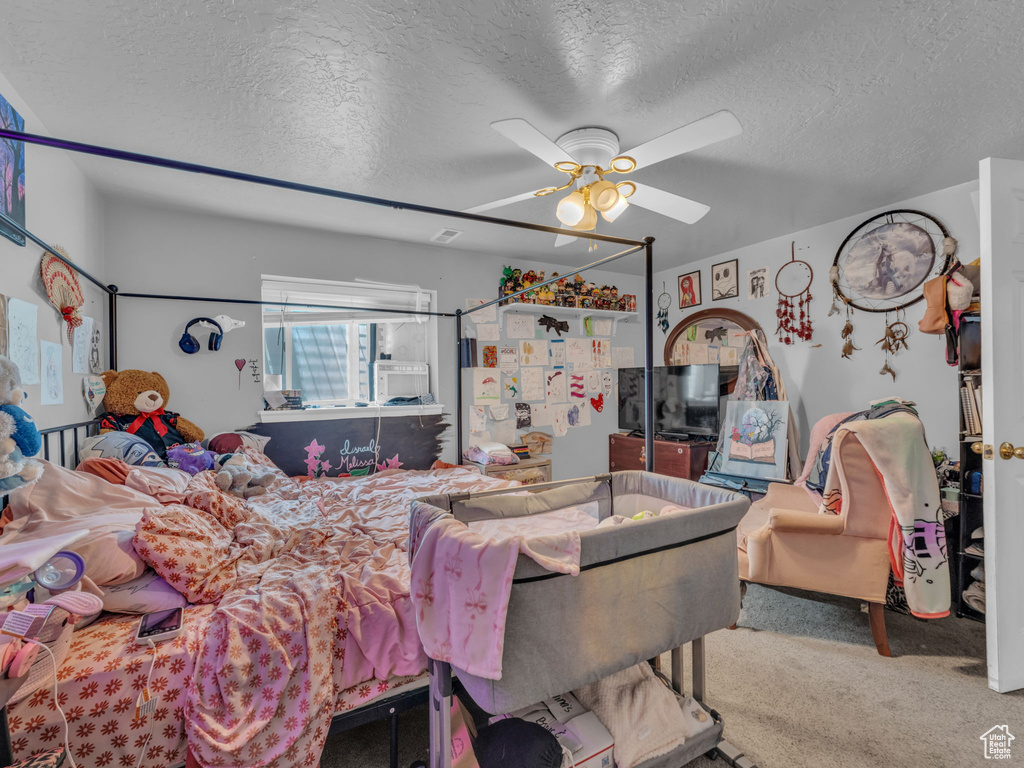 Bedroom with carpet, a textured ceiling, and a ceiling fan