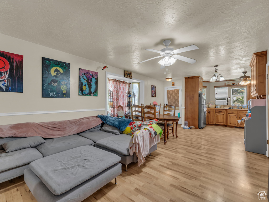 Living room featuring a ceiling fan, light wood finished floors, healthy amount of natural light, and a textured ceiling