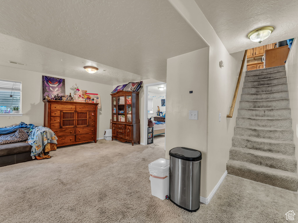 Stairway featuring a textured ceiling and carpet