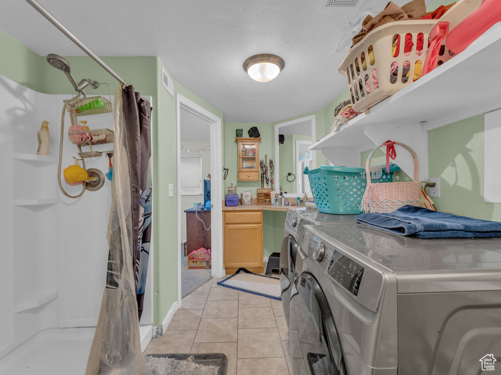Washroom with separate washer and dryer and light tile patterned floors