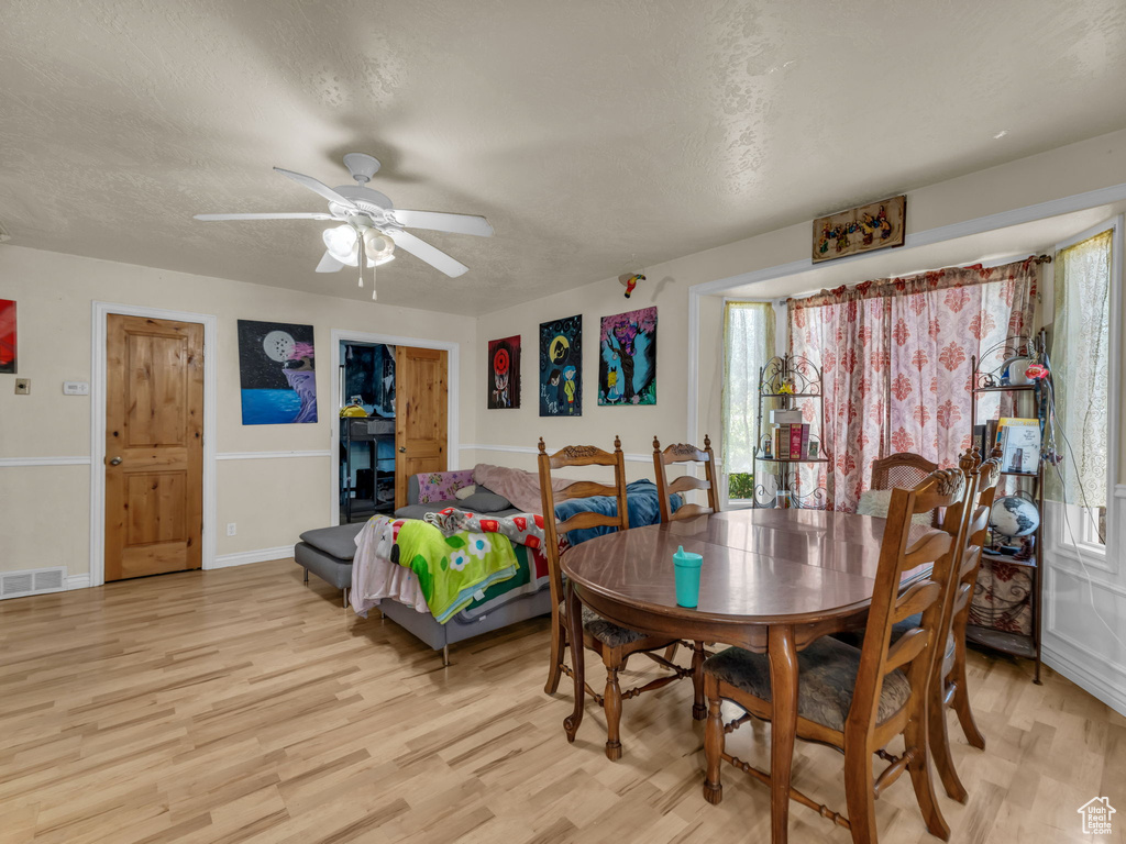 Dining area with light wood-style floors, a ceiling fan, and a textured ceiling