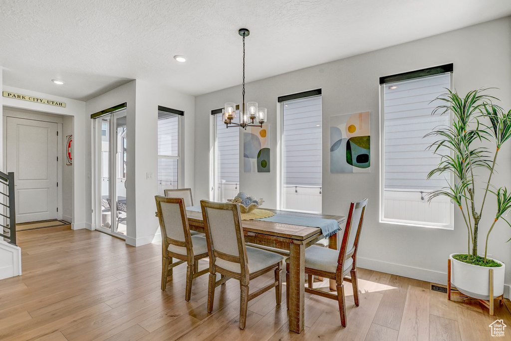 Dining room featuring light wood-style floors, a chandelier, recessed lighting, and a textured ceiling