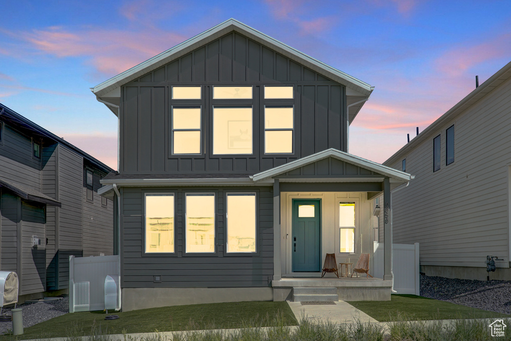 View of front of property featuring board and batten siding, covered porch, and a front lawn