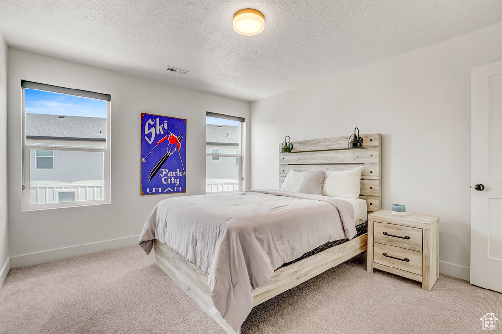 Bedroom with light carpet and a textured ceiling