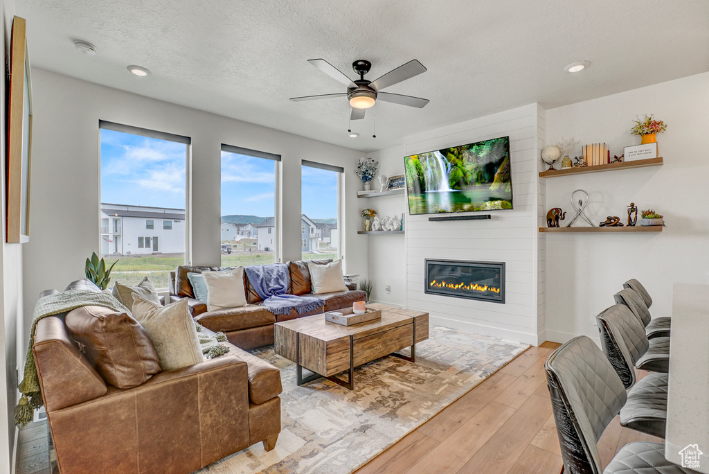 Living area featuring ceiling fan, a large fireplace, hardwood / wood-style floors, and recessed lighting