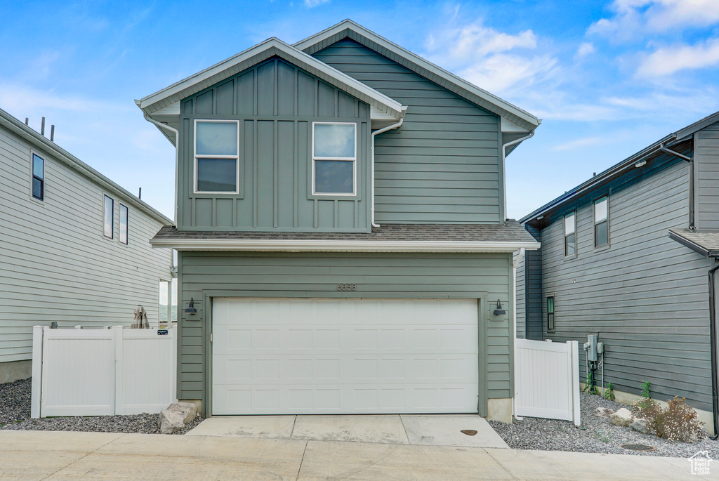 View of front of house with board and batten siding, concrete driveway, a garage, and a shingled roof