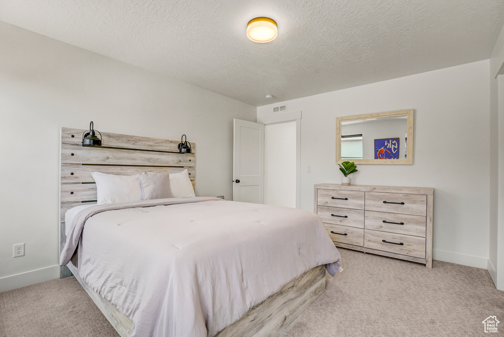 Bedroom featuring light carpet and a textured ceiling