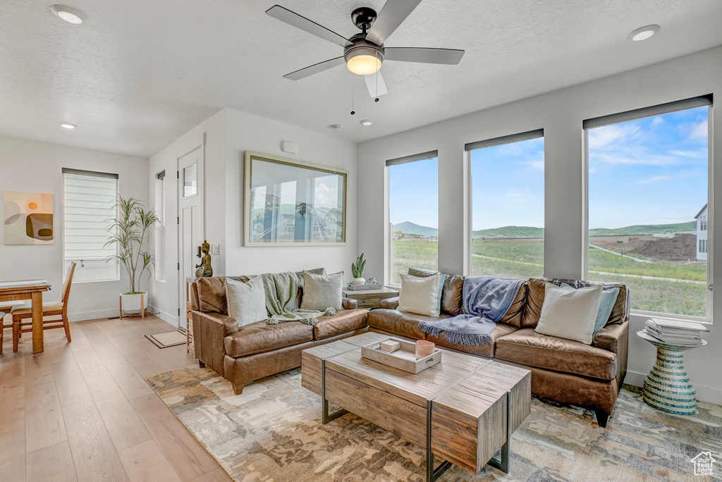 Living area featuring ceiling fan, light wood-type flooring, recessed lighting, a textured ceiling, and a mountain view