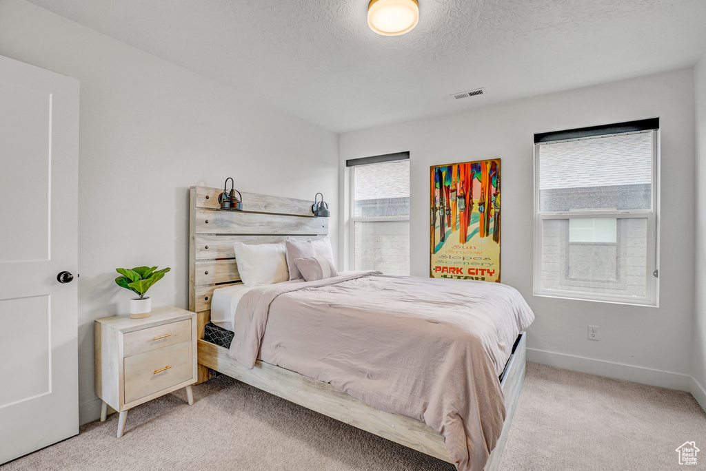 Bedroom featuring light carpet and a textured ceiling