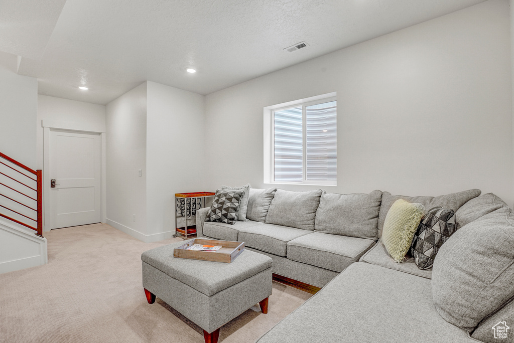 Living room featuring light colored carpet, stairs, and recessed lighting